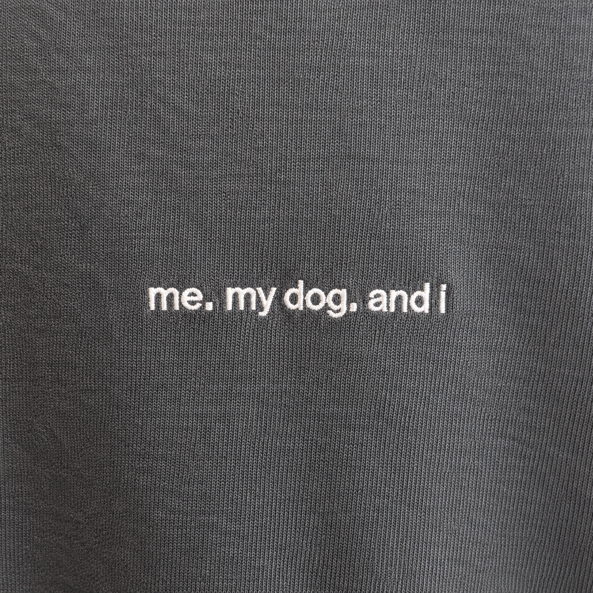 Nahaufnahme der weißen Stickerei me. my dog. and i auf verwaschenem schwarzem Baumwollstoff