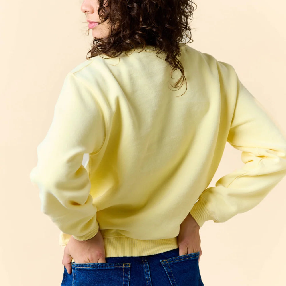 Rückansicht des buttergelben Kindness Sweaters am Model.