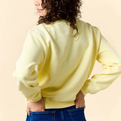 Rückansicht des buttergelben Kindness Sweaters am Model.