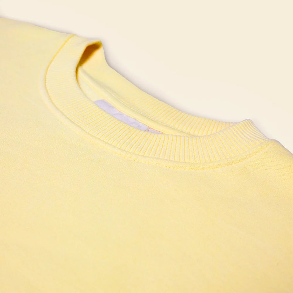 Nahaufnahme des Rundhalsausschnitts am buttergelben popeia Sweater.