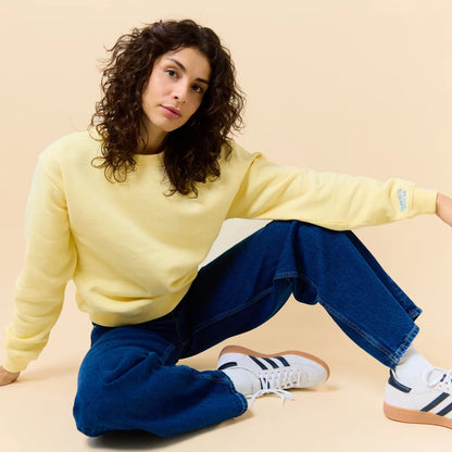 Model trägt den Kindness Sweater in Buttergelb zu einer blauen Jeans.