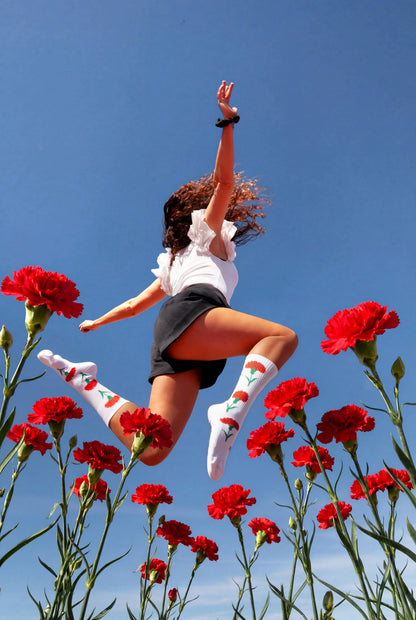 Person mit weißen Freedom Socken springt über ein Feld aus roten Nelken